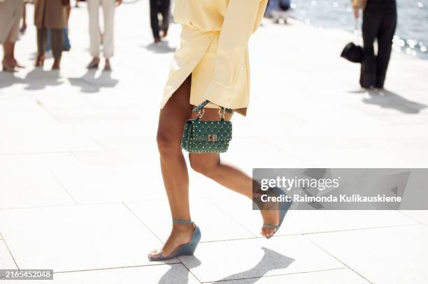 Gili Biegun wears pale yellow leather mini dress, green bag and light blue shoes outside OpéraSport show during the Copenhagen Fashion Week SS25 on...