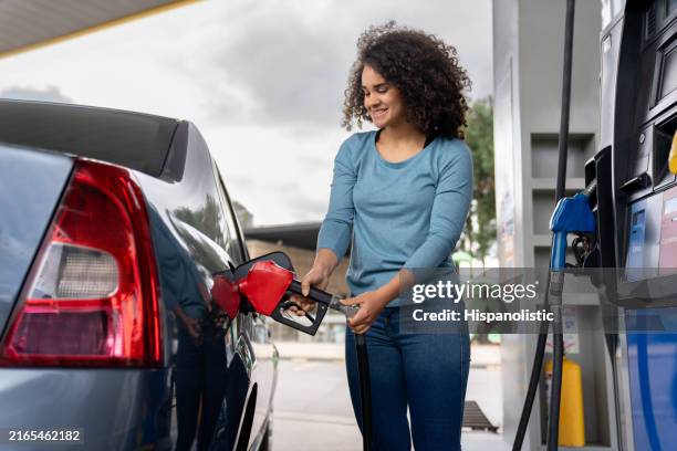 frau, die ihr auto an einer tankstelle tanken - tanken stock-fotos und bilder