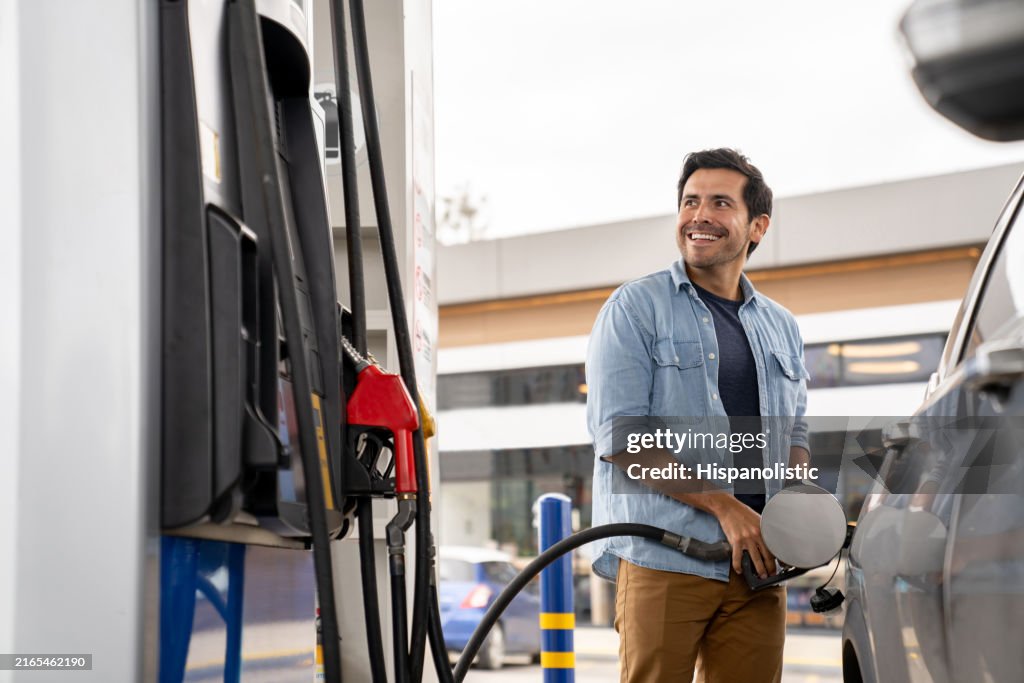 Happy man putting gas in his car at a petrol station