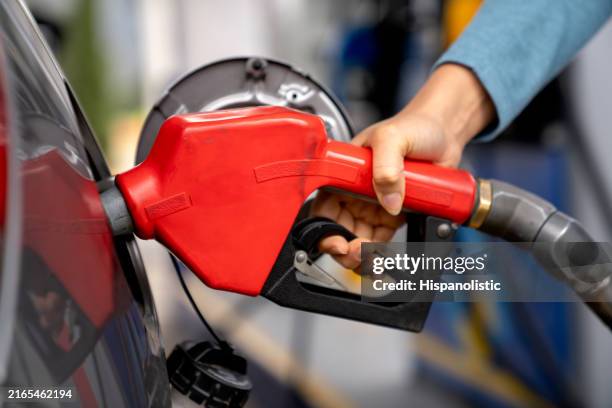 woman refueling her car at a gas station - petrol nozzle stock pictures, royalty-free photos & images