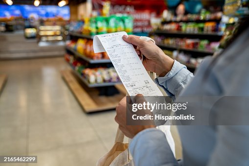 Frau, die in einem Supermarkt einkauft und ihre Quittung überprüft Frau, die in einem Supermarkt einkauft und ihre Quittung überprüft