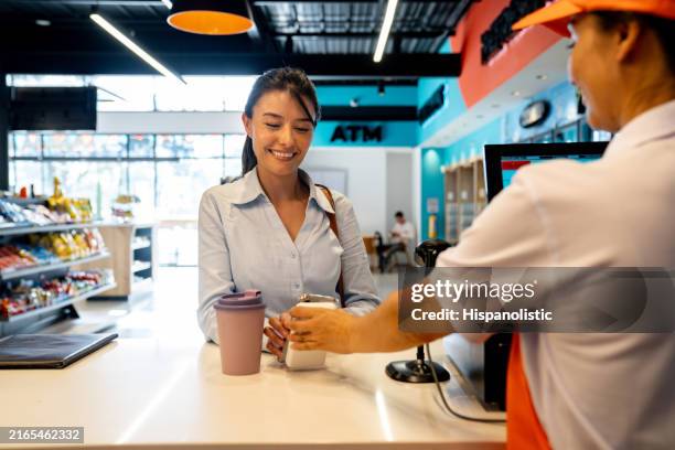 happy customer making a mobile payment at a coffee shop - gemakswinkel stockfoto's en -beelden