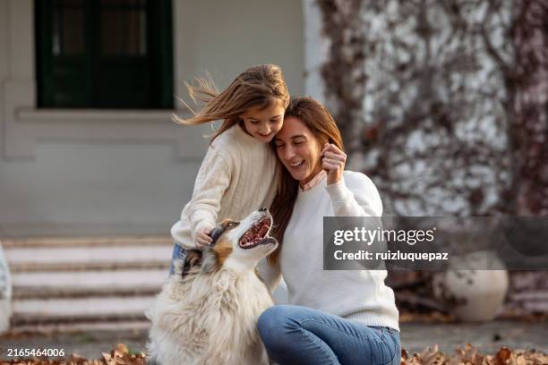 portrait of mother and daughter playing with their dog outdoors in autumn - kids playing in the leaves stock pictures, royalty-free photos & images