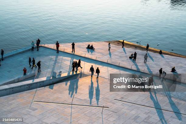 people walking along oslo's harbour promenade, oslo, norway - stadsuitbreiding stockfoto's en -beelden