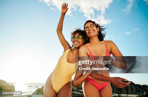 Two young women in swimwear laughing during a beach day in summer Two young women in swimwear laughing during a beach day in summer