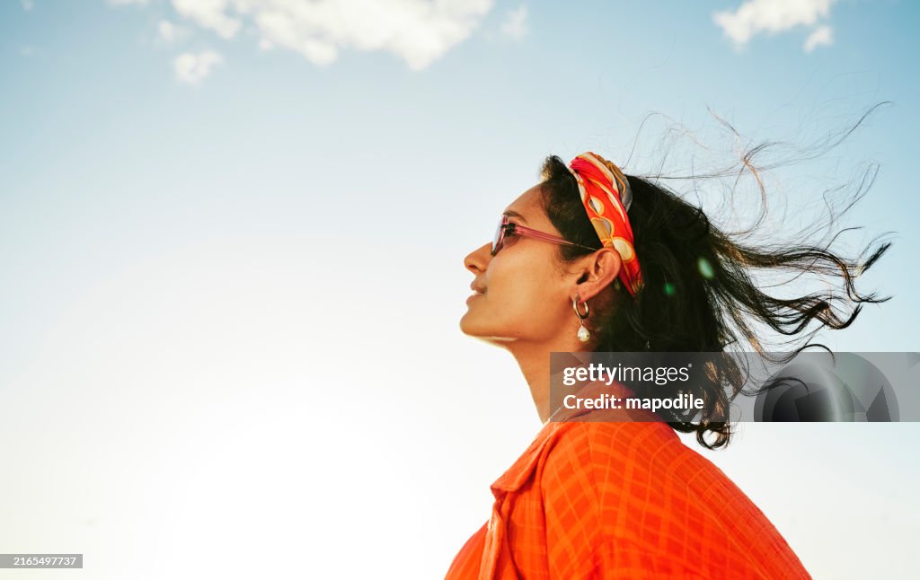 Junge Frau, die an einem sonnigen Tag in den Himmel schaut und lächelt