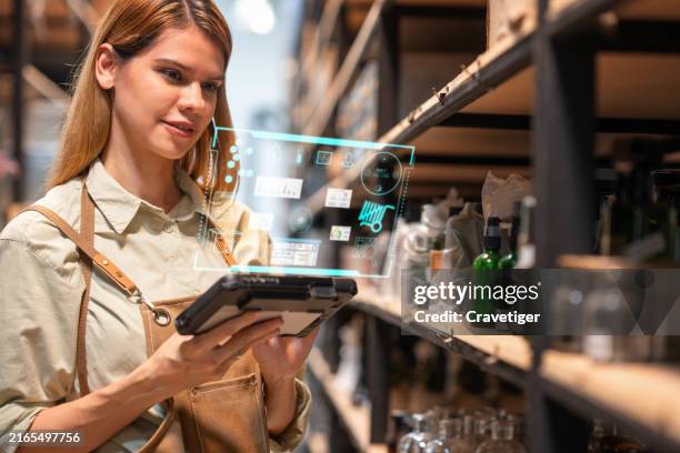 the female manager of the home decor store uses a digitization display with a digital tablet to generate data and information on a product in the inventory stock in the warehouse area before sending it to the customer. - personalizzazione foto e immagini stock