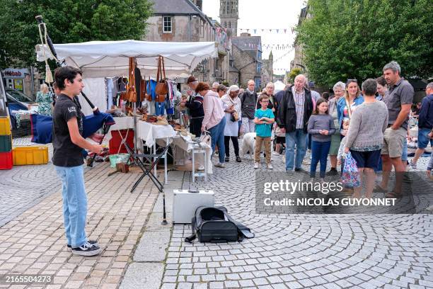 Young Breton boy plays the bagpipes during the traditional weekly summer market in Saint Pol de Leon, France, on August 6, 2024.