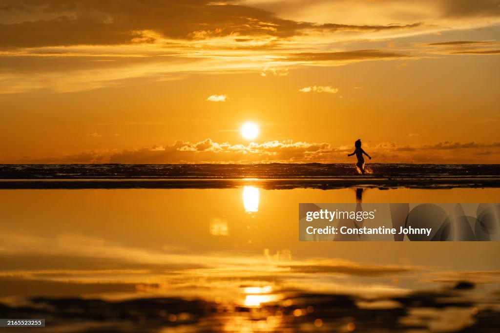 Kid Silhouette Running at Beach Against Golden Sky