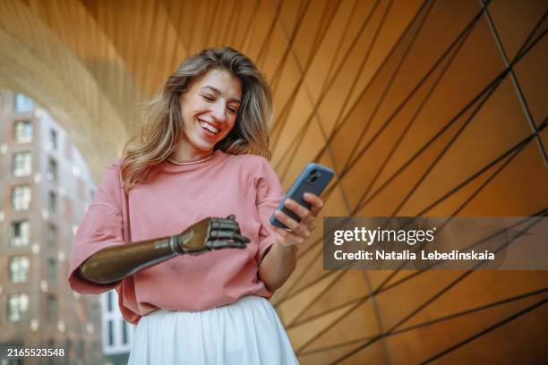 woman with a prosthetic arm and smartphone enjoying the urban environment near tall buildings - self improvement stock pictures, royalty-free photos & images