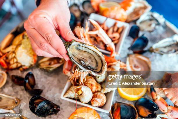 man eating oysters and various seafood at luxury restaurant, paris, france - fruits de mer photos et images de collection