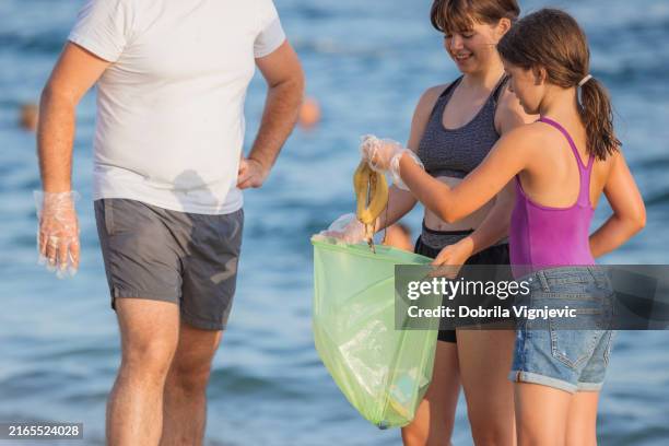 girls cleaning the beach from litter - climate activist stock pictures, royalty-free photos & images