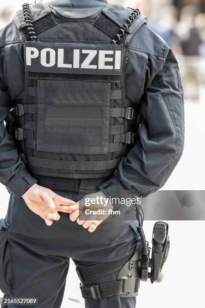german police officer with a gun observes the town - duitse cultuur stockfoto's en -beelden