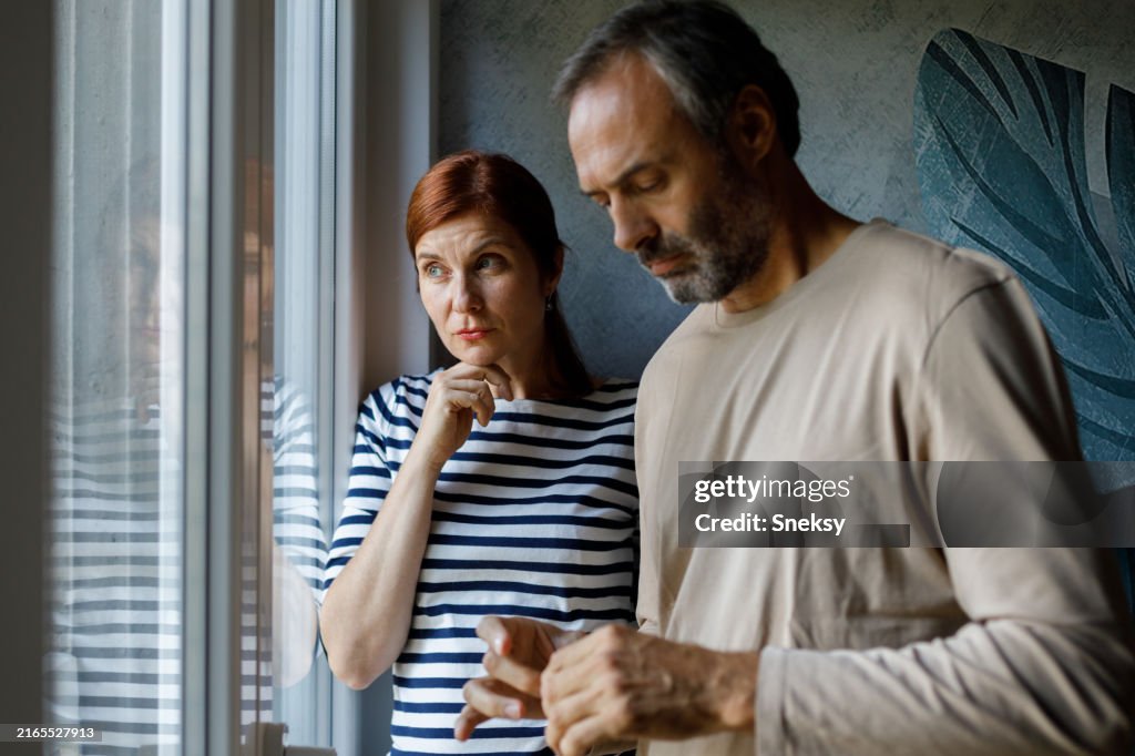 Reifes Paar, das zu Hause auf dem Sofa sitzt.