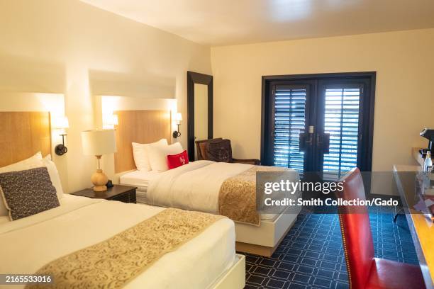 Interior of a hotel room with two double beds, modern decor, and a seating area near French doors at the Hotel Valencia, San Jose, California, August...