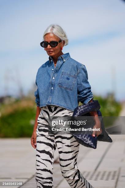 Guest wears black sunglasses, red hoop earrings navy blue denim jean cropped long sleeve shirt, white and black animal pattern/print high waisted...