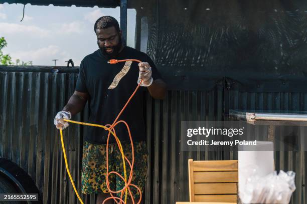 bbq food truck owner untangling two electrical extension cords while setting up for a lunch catering event - untangling stock pictures, royalty-free photos & images