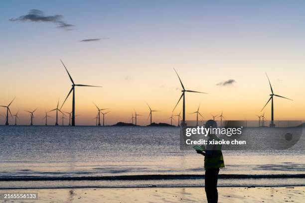 offshore-windparks mit elektrikern, die im morgengrauen arbeiten - grünes wirtschaften stock-fotos und bilder