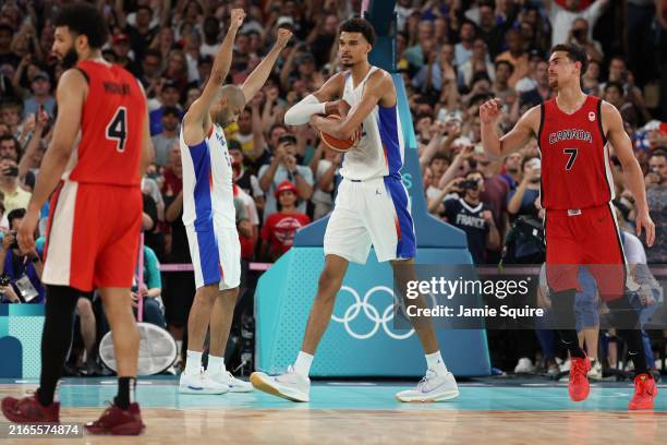 Nicolas Batum and Victor Wembanyama of Team France react while Jamal Murray and Dwight Powell of Team Canada look on after Team France's victory...