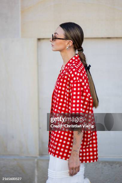 Guest wears red white checkered button shirt, white skirt outside Lovechild 1979 during day two of the Copenhagen Fashion Week SS25 on August 06,...