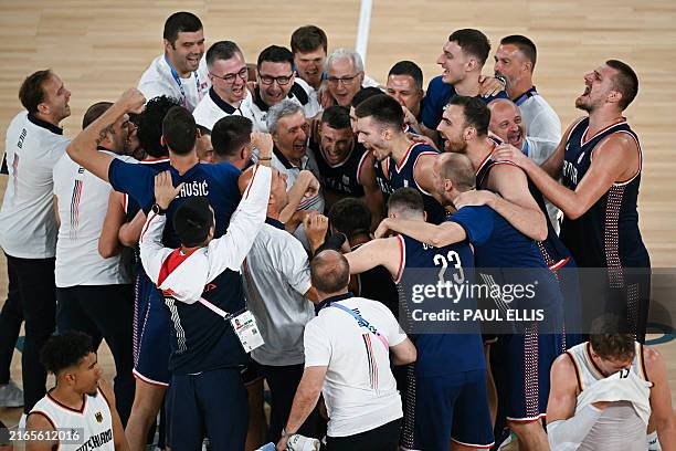 Serbia's team players surround Serbia's coach Svetislav Pesic as they celebrate winning the men's Bronze Medal basketball match between Germany and...