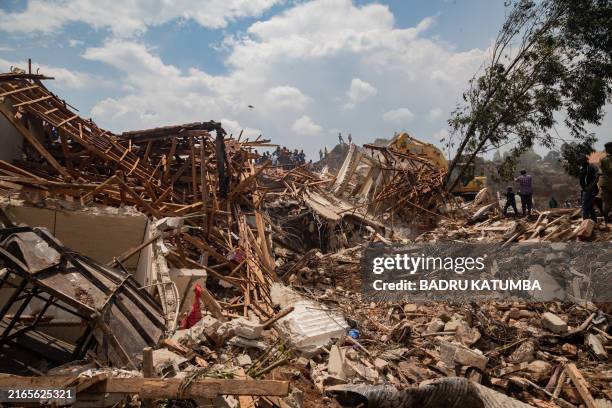 People look on as an excavator helps search for people trapped under debris after a landfill collapsed in Kampala on August 10, 2024. Eight people...