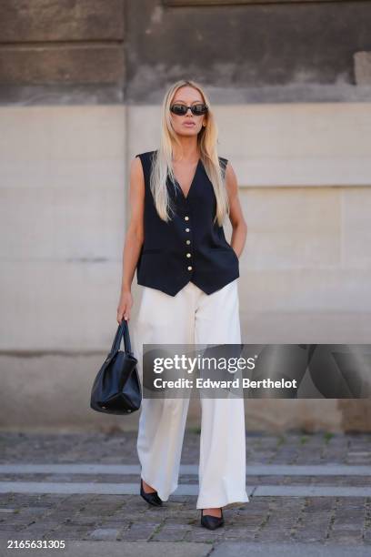Guest wears black sunglasses, black vest, white loose pants, black leather bag, black leather heels, outside Lovechild 1979, during the Copenhagen...