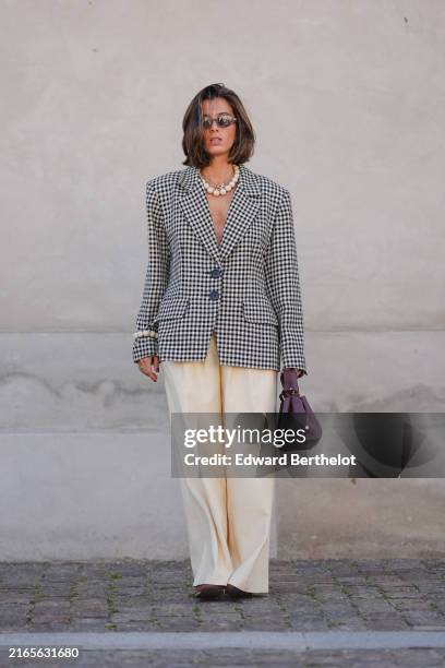 Guest wears black sunglasses, silver necklace, white beaded necklace, black and white pattern oversized blazer jacket, silver rings, white pearl...