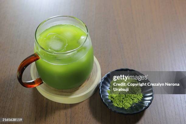 iced matcha in a transparent coffee mug cup. green tea with iced cubes - superfood stock-fotos und bilder