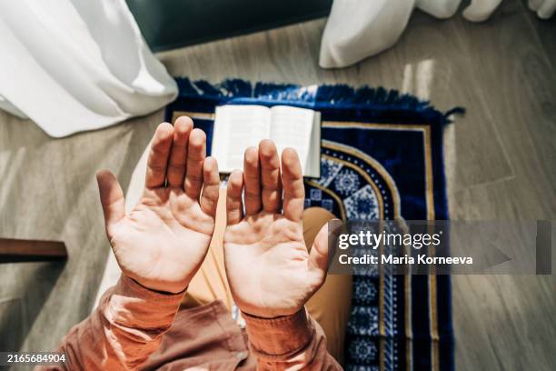 muslim man praying in a hotel while traveling. - alfombra de oración fotografías e imágenes de stock