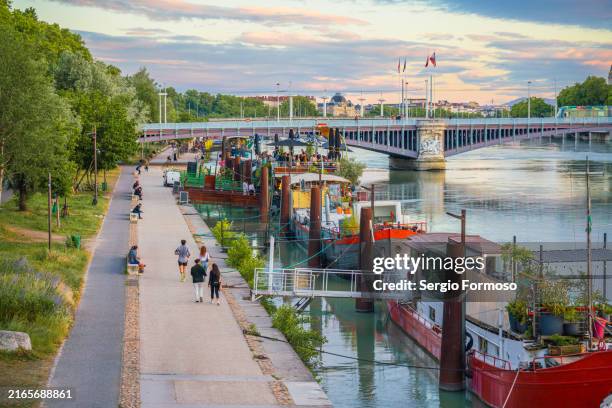vibrant riverside activity along the rhone river in lyon, france, during golden hour - péniche-commerciale photos et images de collection