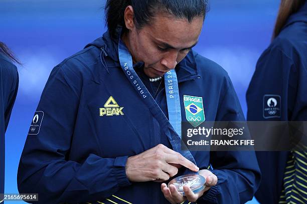 Brazil's silver medallist forward Marta looks at her trophy on the podium after the women's gold medal final football match between Brazil and US...