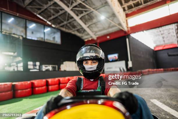 portrait of a mature woman driving on a go-kart track - gokartfahren stock-fotos und bilder