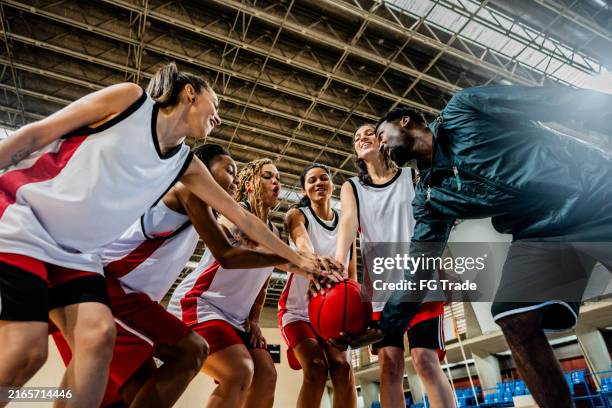 basketball coach and players with hands clasped on sports court - female basketball team stock pictures, royalty-free photos & images