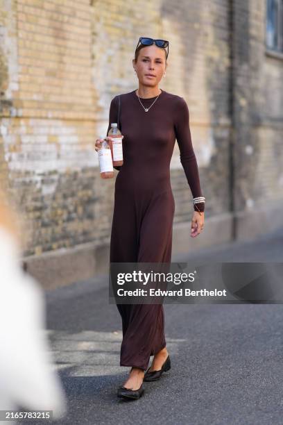 Guest wears black sunglasses, white earrings, silver necklaces, dark brown long sleeve maxi dress, silver bracelets, shiny black ballerina mini heels...