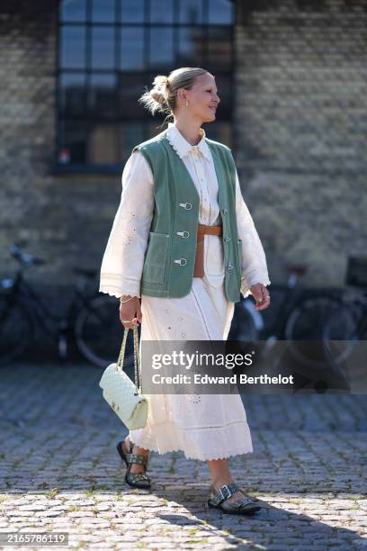 Guest wears white button up pattern long sleeve shirt, light green oversized vest, light brown belt bag, silver rings, gold bracelets, white pattern...
