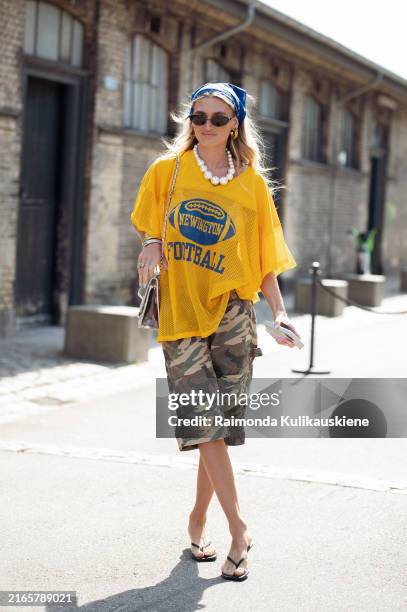 Guest wears camouflage shorts, yellow sport top, Chanel bag and blue head scarf outside the Deadwood show during day three of the Copenhagen Fashion...