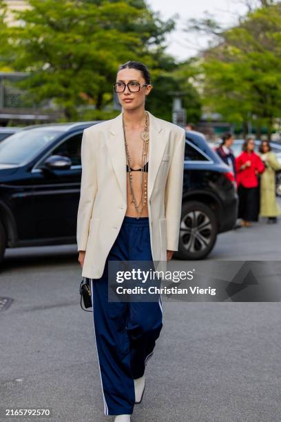 Chelsey Weimar wears creme white oversized blazer, glasses, necklace, navy tracksuit pants, black bag outside Baum & Pferdgarten during day three of...