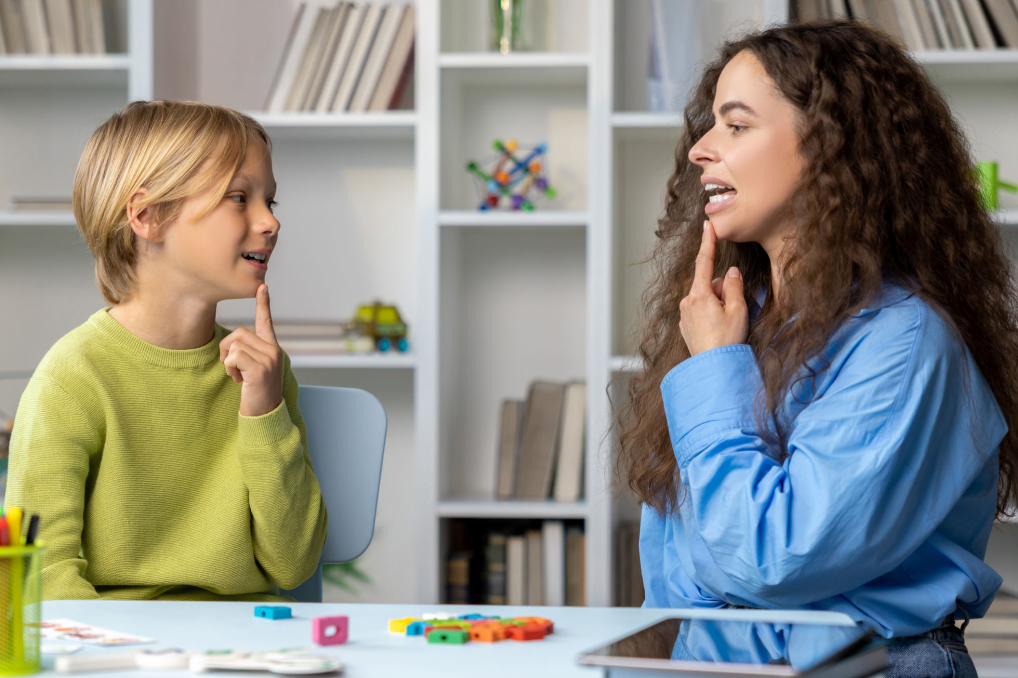 Blonde boy exercising with speech therapist and making efforts Blonde boy exercising with speech therapist and making efforts