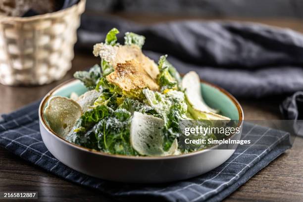 closeup of a fresh caesar salad, with romaine lettuce hearts, croutons, parmesan cheese and dressing. - green salad stock pictures, royalty-free photos & images