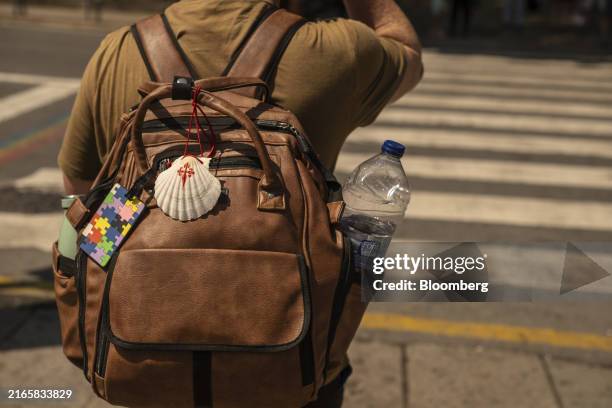 Pilgrim with a shell from the Camino de Santiago and a bottle of water in his rucksack during high temperatures in Santiago de Compostela, Spain, on...