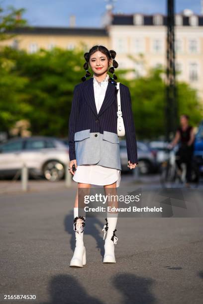 Guest wears silver necklace, white button up long sleeve mini dress, navy blue gray lined light gray oversized blazer jacket, white leather bag,...