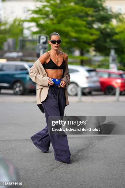 Vera van Erp wears black sunglasses, gold necklace, light brown oversized blazer jacket, black bralette, navy blue high waisted pants, outside Baum...