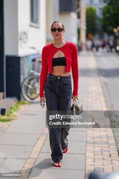 Guest wears dark brown sunglasses, silver necklace, black bandeau, bright red sweater, dark brown pattern/print Louis Vuitton canvas bag, black denim...