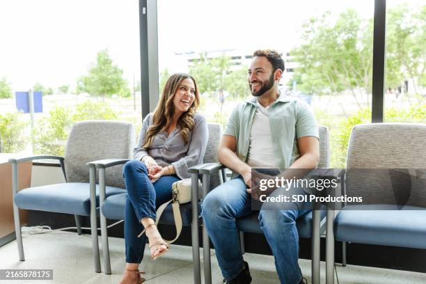 young adult couple sit together in the lobby - sala de espera imagens e fotografias de stock