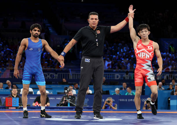 Aman Aman of Team India looks on as Match Referee Mehmet Gurhan Yucel raises the hand of Rei Higuchi of Team Japan to announce the winner of the...
