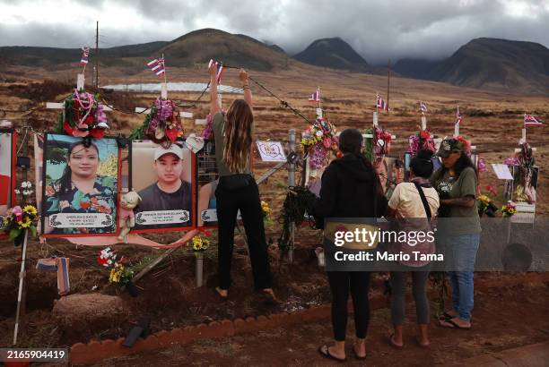Lei is placed over memorial crosses before sunrise at a public hillside memorial to Lahaina wildfire victims, during a ceremony organized by Malu i...