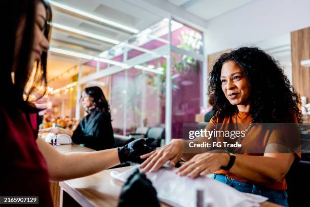 mature woman talking with manicure on nail salon - nail salon stock pictures, royalty-free photos & images