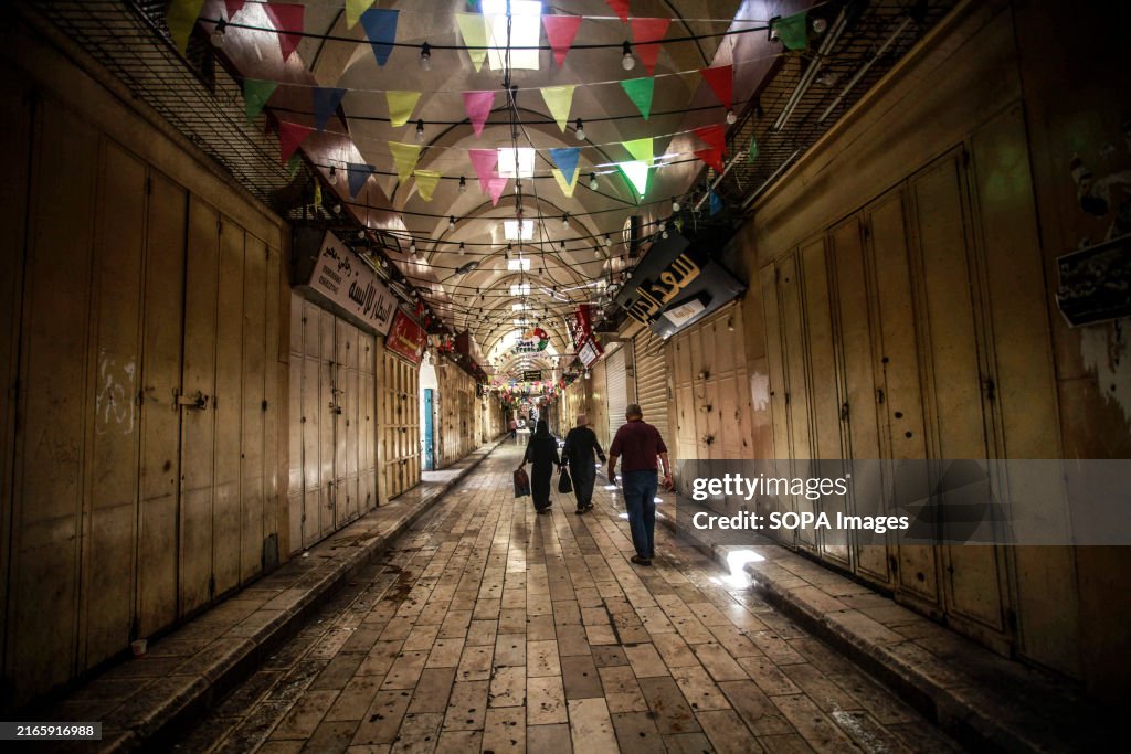 Palestinians walk through a deserted commercial area in...
