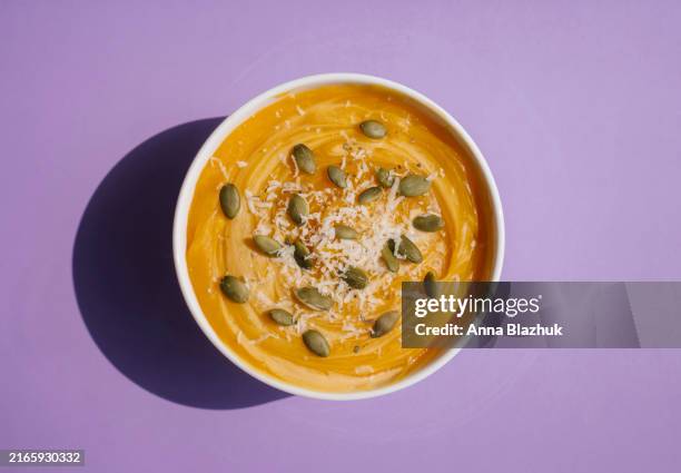 autumn seasonal meal, pumpkin soup with seed and cheese in bright sunlight - pumpkin soup stock pictures, royalty-free photos & images